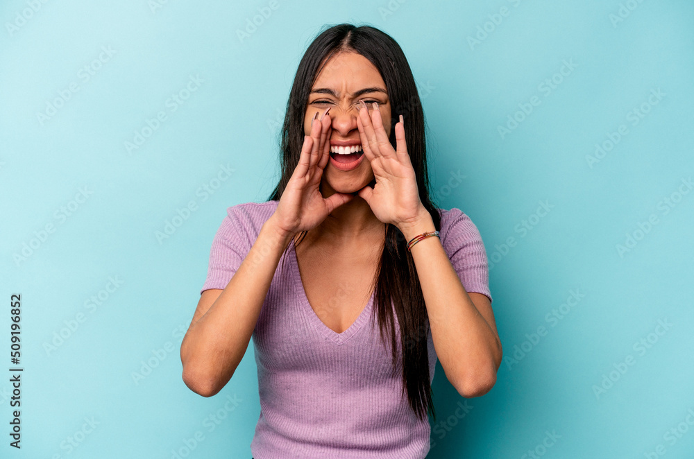 Young hispanic woman isolated on blue background saying a gossip, pointing to side reporting something. Young hispanic woman isolated on blue background saying a gossip, pointing to side reporting something.
