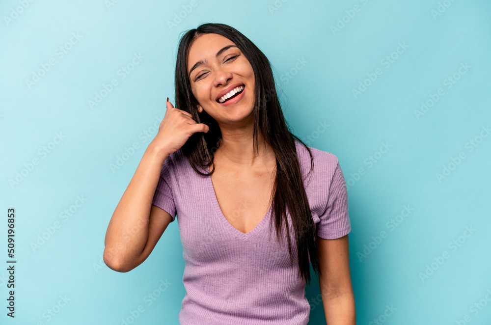 Young hispanic woman isolated on blue background showing a mobile phone call gesture with fingers. Young hispanic woman isolated on blue background showing a mobile phone call gesture with fingers.