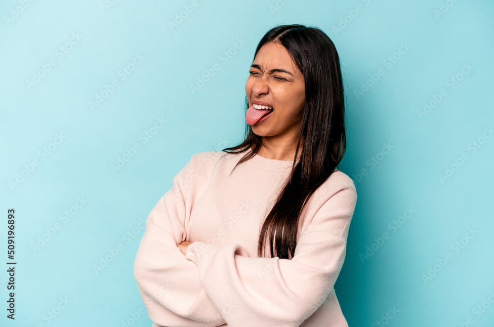 Young hispanic woman isolated on blue background funny and friendly sticking out tongue. Young hispanic woman isolated on blue background funny and friendly sticking out tongue.