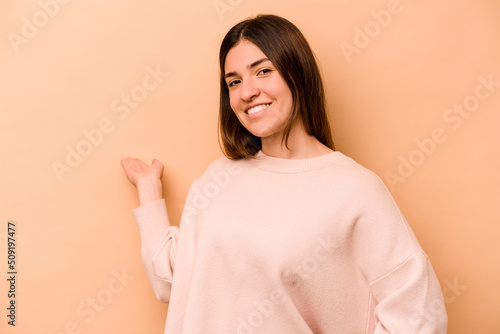 Young hispanic woman isolated on beige background showing a welcome expression.