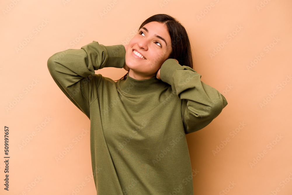Young hispanic woman isolated on beige background feeling confident, with hands behind the head. Young hispanic woman isolated on beige background feeling confident, with hands behind the head.