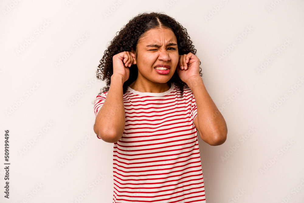 Young African American woman isolated on white background covering ears with fingers, stressed and desperate by a loudly ambient. Young African American woman isolated on white background covering ears with fingers, stressed and desperate by a loudly ambient.