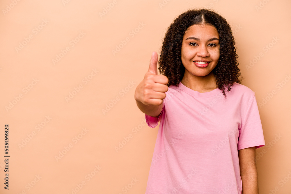 Young African American woman isolated on beige background smiling and raising thumb up Young African American woman isolated on beige background smiling and raising thumb up