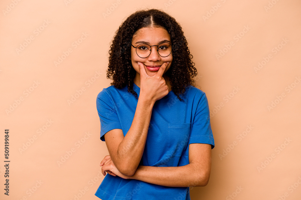 Young African American woman isolated on beige background doubting between two options. Young African American woman isolated on beige background doubting between two options.