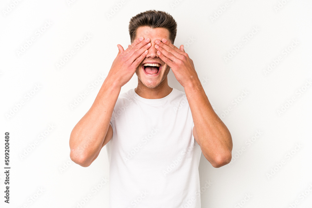 Young caucasian man isolated on white background covers eyes with hands, smiles broadly waiting for a surprise. Young caucasian man isolated on white background covers eyes with hands, smiles broadly waiting for a surprise.