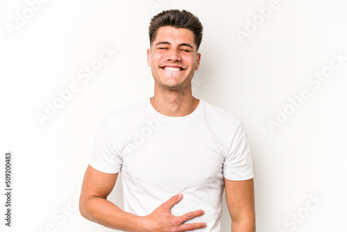 Young caucasian man isolated on white background touches tummy, smiles gently, eating and satisfaction concept.
