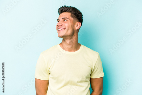 Young caucasian man isolated on blue background relaxed and happy laughing, neck stretched showing teeth.
