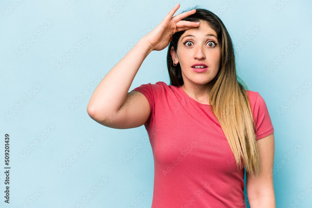 Young caucasian woman isolated on blue background shouts loud, keeps eyes opened and hands tense. Young caucasian woman isolated on blue background shouts loud, keeps eyes opened and hands tense.