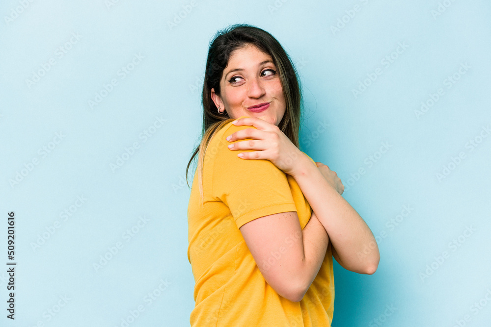 Young caucasian woman isolated on blue background hugs, smiling carefree and happy. Young caucasian woman isolated on blue background hugs, smiling carefree and happy.