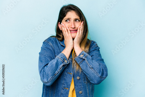 Young caucasian woman isolated on blue background scared and afraid.