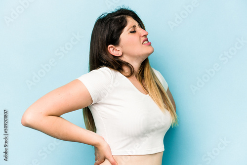 Young caucasian woman isolated on blue background suffering a back pain.