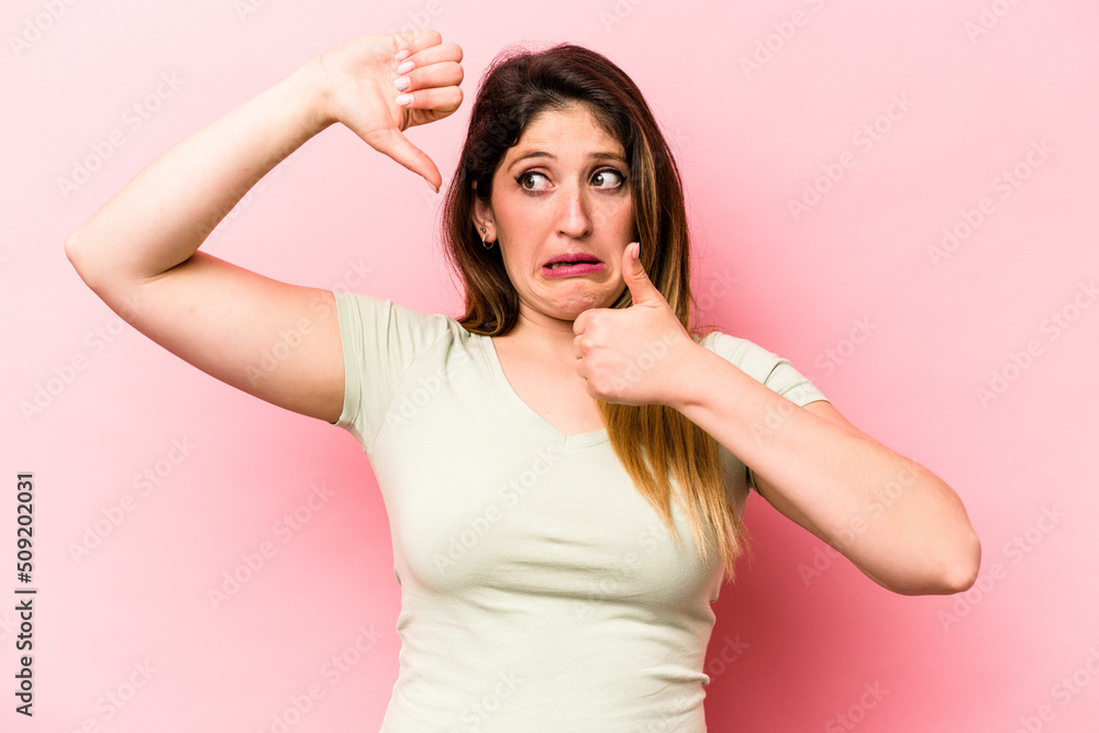 Young caucasian woman isolated on pink background showing thumbs up and thumbs down, difficult choose concept Young caucasian woman isolated on pink background showing thumbs up and thumbs down, difficult choose concept