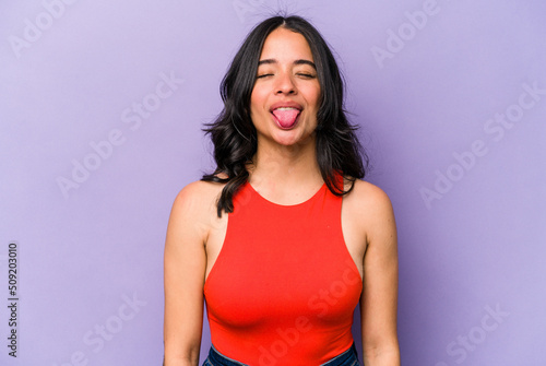 Photographie Young hispanic woman isolated on purple background funny and friendly sticking out tongue