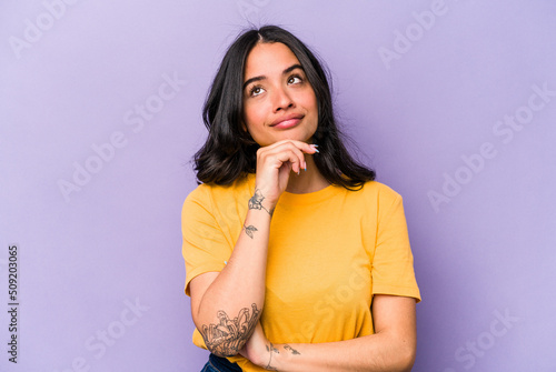 Obraz na plátne Young hispanic woman isolated on purple background thinking and looking up, being reflective, contemplating, having a fantasy