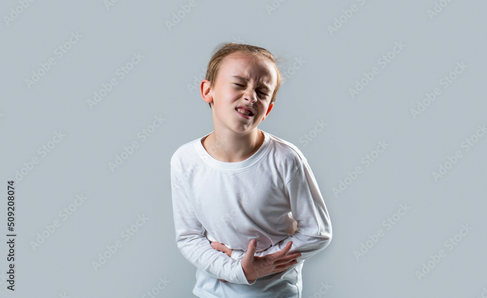 Stomach pain. Teen boy with stomachache. Child having terrible pain in stomach. Diarrhea or gastroenteritis health problem. Child has stomachache with food poisoning. Child holding hands on belly - obrazy, fototapety, plakaty 