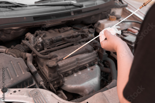 A woman's hands checking the oil level of a car with an oil dipstick.