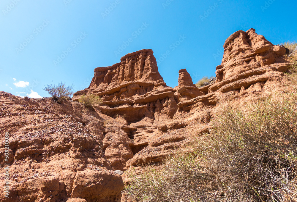 Red tales from clay. Issyk-Kul region in Kyrgyzstan. Beautiful mountain landscape. Tourism and travel.
