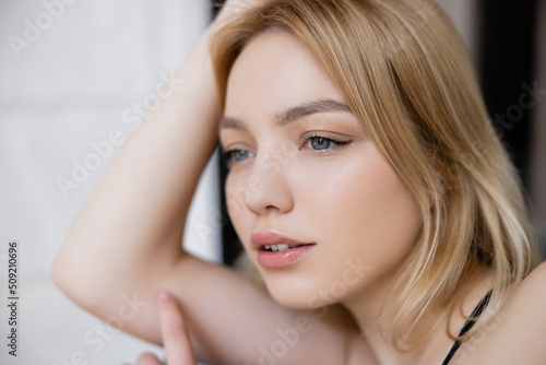Portrait of blonde woman looking away at home.