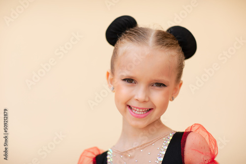 gymnastics girl with make up and hair dressing posing on beige background