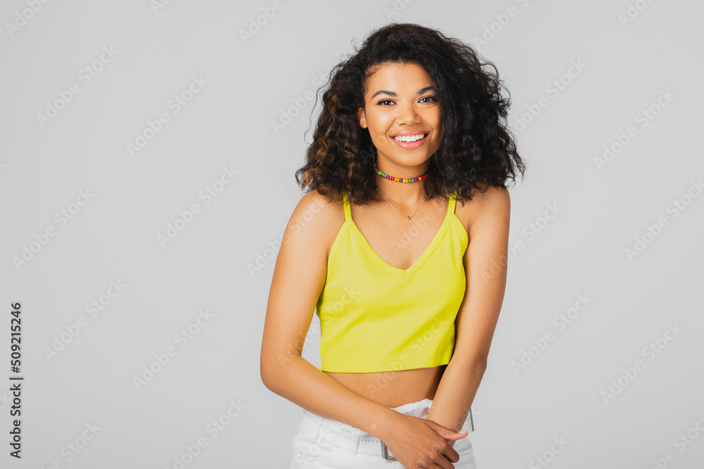 cheerful african american woman in yellow crop top smiling isolated on grey. cheerful african american woman in yellow crop top smiling isolated on grey.