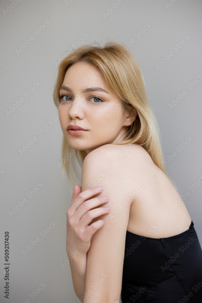 Portrait of young woman in black dress looking at camera isolated on grey. Portrait of young woman in black dress looking at camera isolated on grey.
