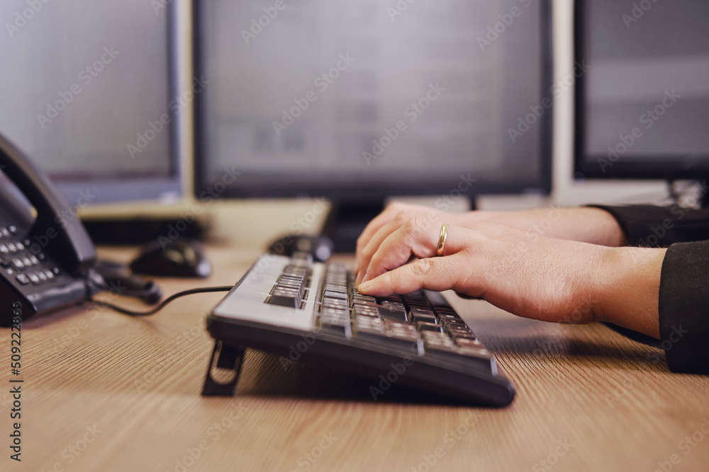 A businessman man is working on a computer keyboard at an office desk, close-up