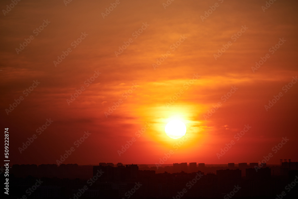 Sunset on a red sky with evening clouds in the city. The setting evening sun over the city with high-rise buildings Sunset on a red sky with evening clouds in the city. The setting evening sun over the city with high-rise buildings