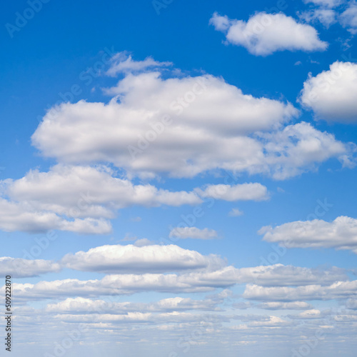 White cumulus clouds in the blue sky. Bright beautiful sky, copy space background