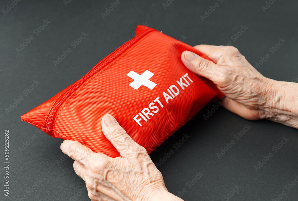 Old wrinkled hands holding first aid kit. Old wrinkled hands holding first aid kit.