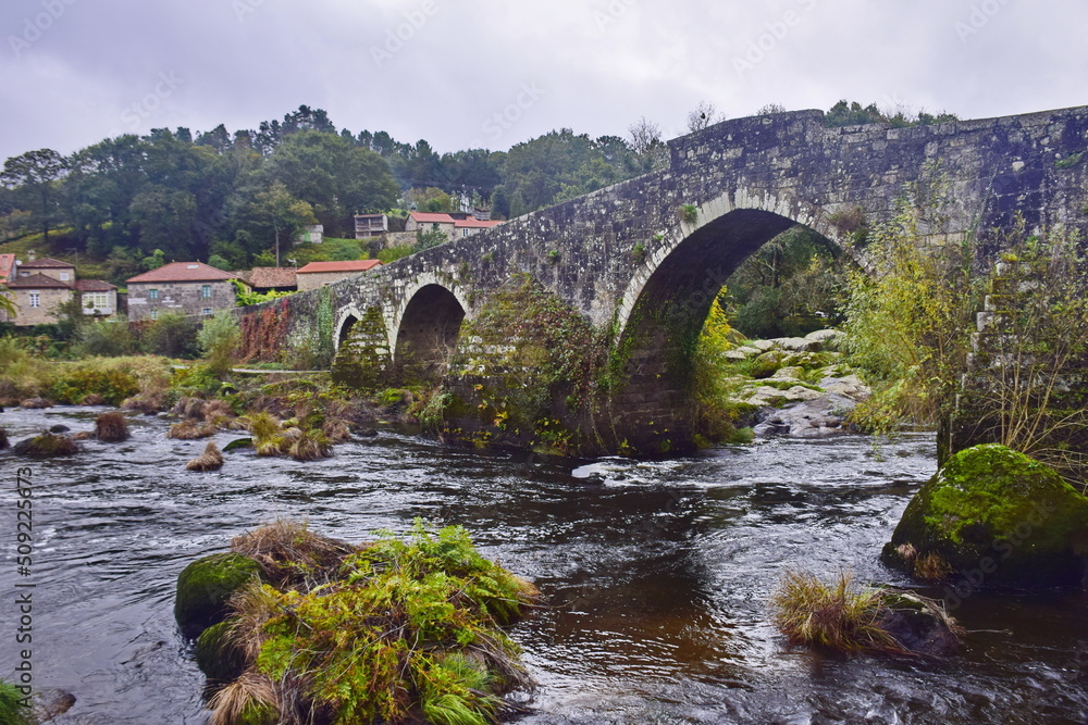 Old stone bridge with arches across the river. The Way of St. James, Northern Route, Spain.