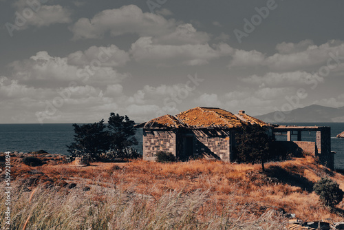 An abandoned stone house next to a fig tree and a well by the sea in Foça, Izmir. Dramatic view of an abondoned stone house photo