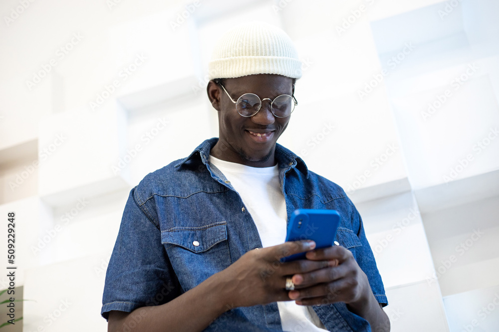 African american guy with glasses typing a message on the phone. African american guy with glasses typing a message on the phone.