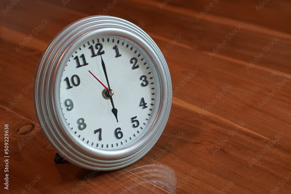 beautiful, at 6 o'clock, alarm clock, silver and white, placed on a wooden floor background, object, fashion,comfortable, modern, copy space beautiful, at 6 o'clock, alarm clock, silver and white, placed on a wooden floor background, object, fashion,comfortable, modern, copy space