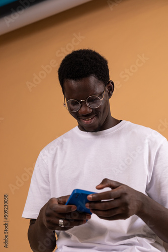 African american man smiling while texting on the phone.