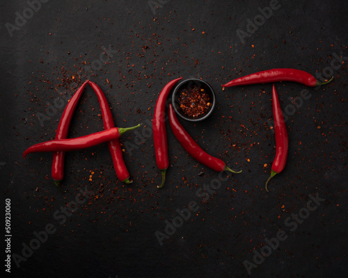 Word "ART" is lined with red chilli pepper. Red peppers creating a word art on black background.Top view. Free copy space.