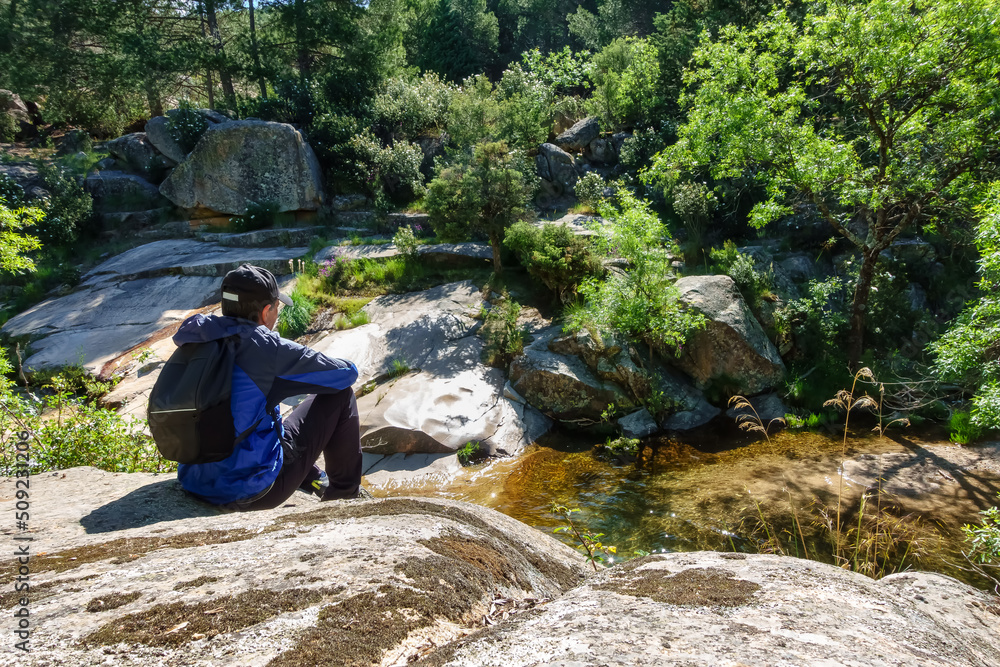 Man sitting on a large rock and enjoying the mountain landscape, Guadarrama Madrid. Man sitting on a large rock and enjoying the mountain landscape, Guadarrama Madrid.
