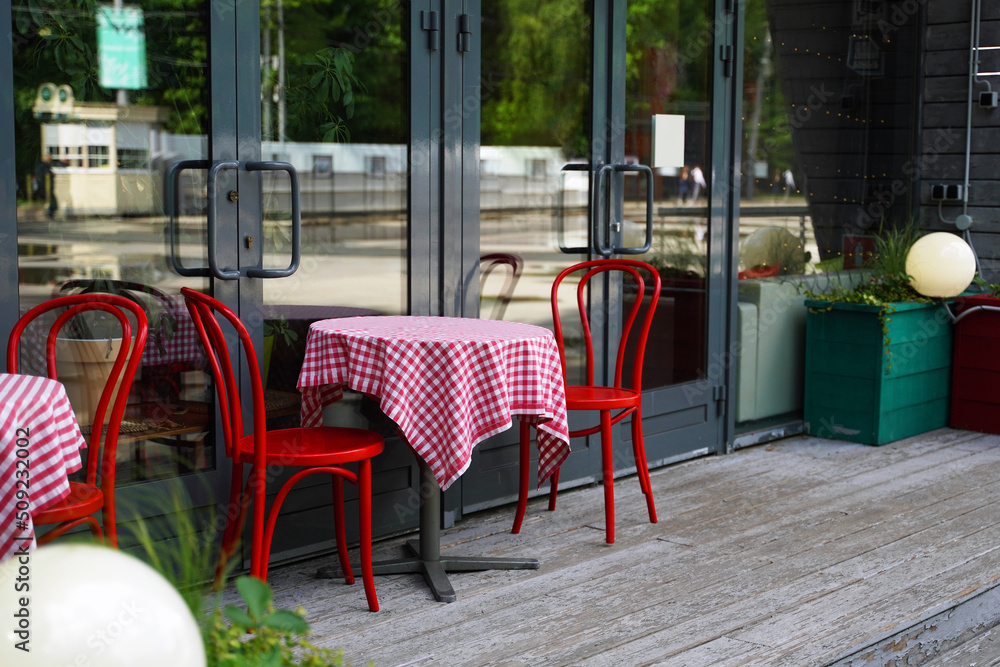 Outdoor cafe red chairs and table with red and white tablecloth
