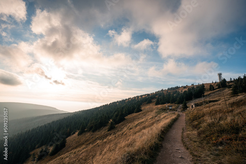 Path leading to top of the Jeseniky mountains, Landscape of warm light sun rays on sky through the clouds over the mountains in Czech republic, Jeseniky