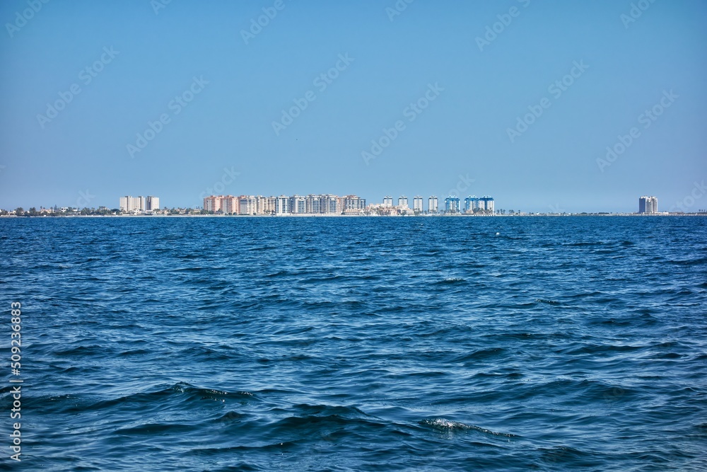 Tourist area of apartments in La Manga del Mar Menor seen from inside said sea on a clear blue sky day