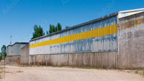 Muro de metal corrugado azul y amarillo en zona industrial