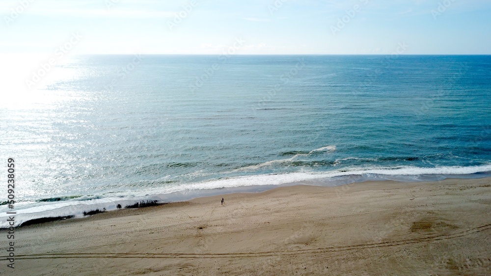 aerial view of a beautiful beach where two people are walking in the evening and the sea reflecting the sun's rays, landscape, Denmark, vacation, holiday aerial view of a beautiful beach where two people are walking in the evening and the sea reflecting the sun's rays, landscape, Denmark, vacation, holiday