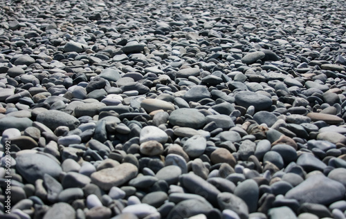 Gray round stones on the beach, pebble beach background