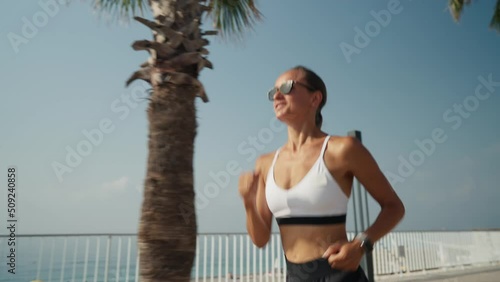 Young caucasian woman running at seaside. Slim girl in sportswear running on promenade by the sea.