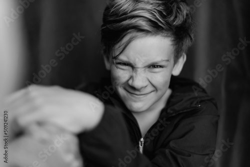 Black and white portrait of teenage boy on dark background. Low key close up shot of a young teen boy. Black and white photography. Selective focus © Rodica