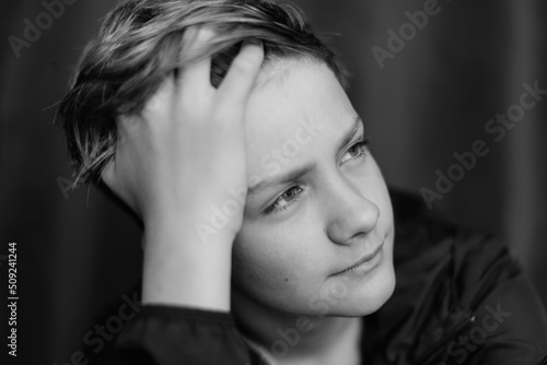 Black and white portrait of teenage boy on dark background. Low key close up shot of a young teen boy. Black and white photography. Selective focus © Rodica