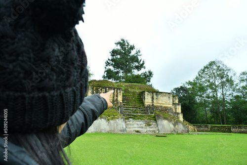 Mujer apuntando a un templo en las ruinas de Iximche en Guatemala. photo