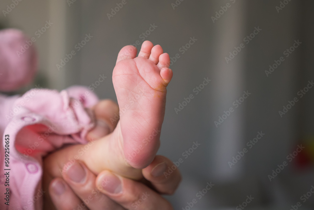 Parent father holding the little Foot of their newborn baby with selective focus Parent father holding the little Foot of their newborn baby with selective focus