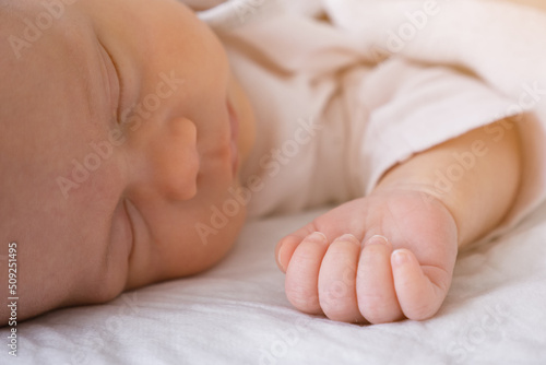 cute little newborn baby girl peacefully sleeps in the nursery on a white cotton bed. selective focus