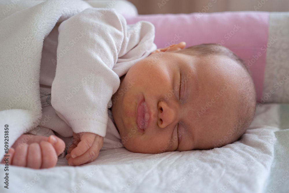 cute little newborn baby girl peacefully sleeps in the nursery on a white cotton bed. selective focus cute little newborn baby girl peacefully sleeps in the nursery on a white cotton bed. selective focus