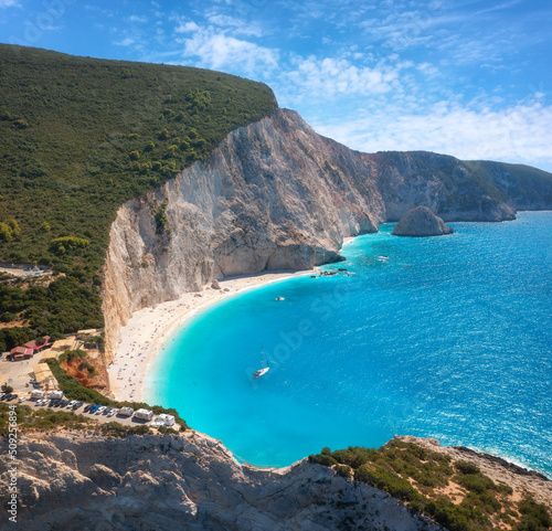 Aerial view of blue sea, rock, sandy beach at sunset in summer. Famous Porto Katsiki, Lefkada island, Greece. Beautiful landscape with sea coast, azure water, sky, clouds. Top view of shore. Travel